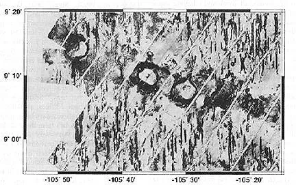 A black and white image showcasing a large rock featuring multiple holes throughout its surface.