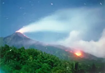 Karangetang in the distance spewing smoke and lava during eruption