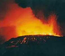 Fiery red streaks of lava spewing from a volcano with cloud of ash illuminated inr ed light