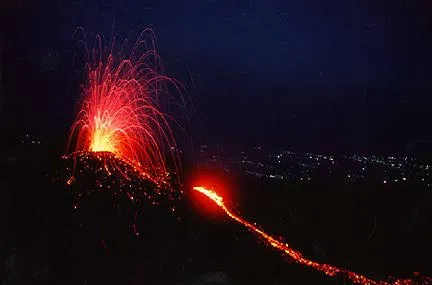 Crater spewing arcs of lava with urban cityscape in background