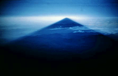 Mount Fuji is famous for its perfectly symmetrical cone. This   photograph shows the shadow of Fuji projected of the adjacent   countryside at sunrise. This photograph, taken in May of 1962, is   copyrighted by Robert Decker. 
